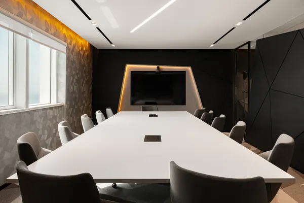 Boardroom with a long conference table and video screen